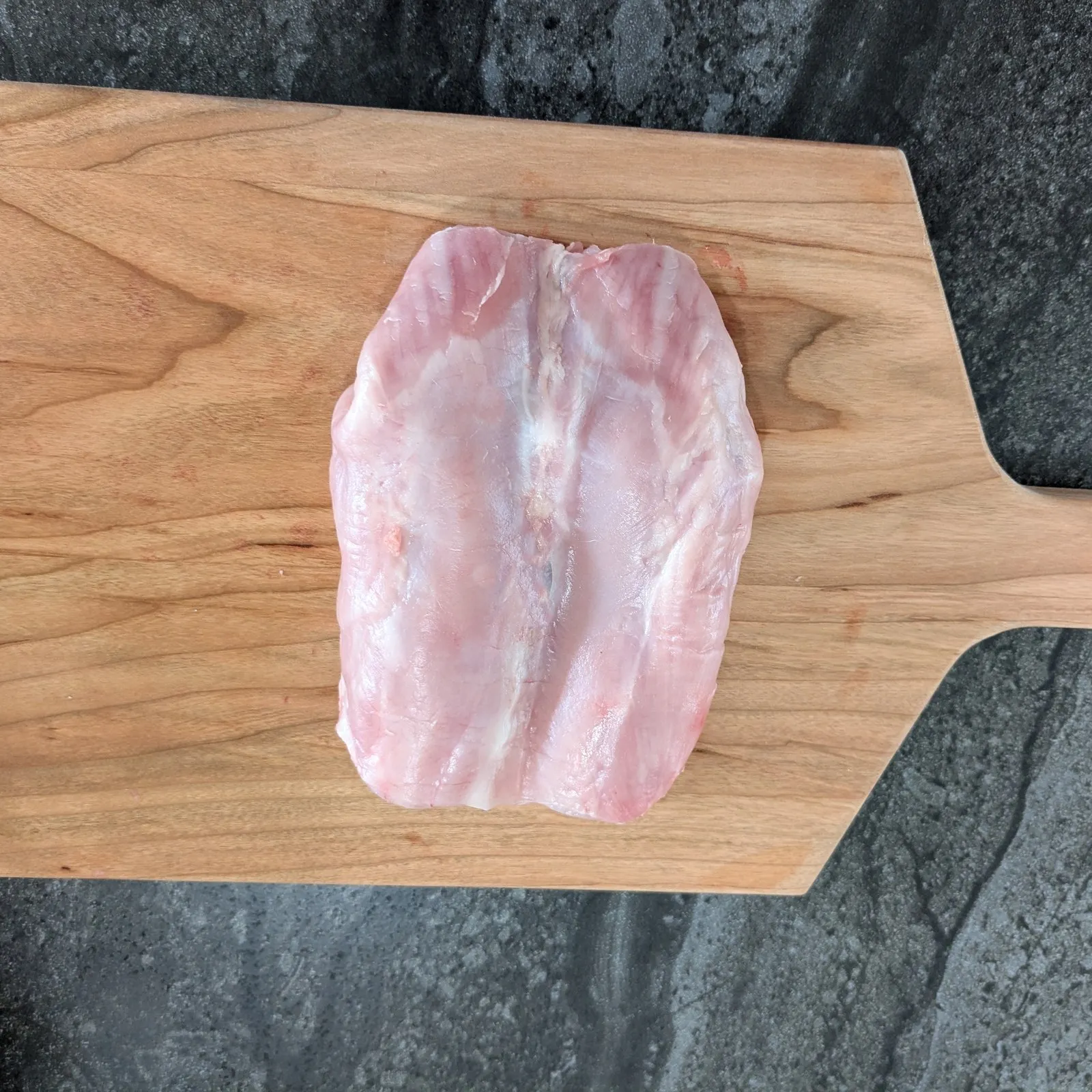 Râble de lapin désossé, cru, sur une planche de bois